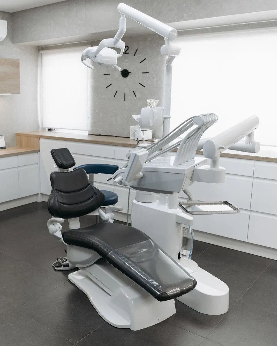 Sillón y equipo dental en un consultorio luminoso de tonos claros.